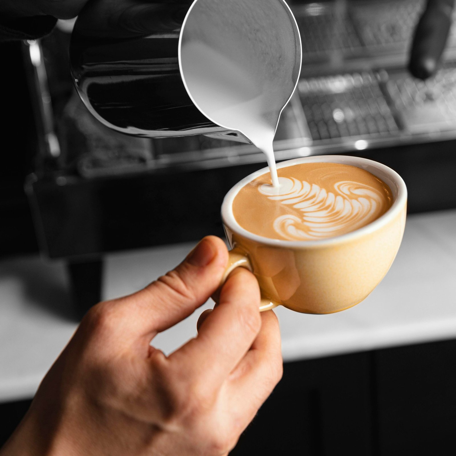 close-up-hand-pouring-milk-coffee-cup